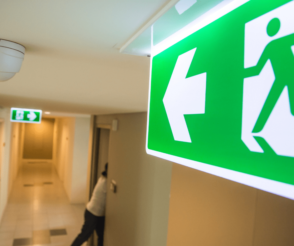 Panneau de sortie de secours dans un couloir, montrant l'importance de la ventouse porte coupe feu pour sécuriser les issues de secours en cas d'incendie.